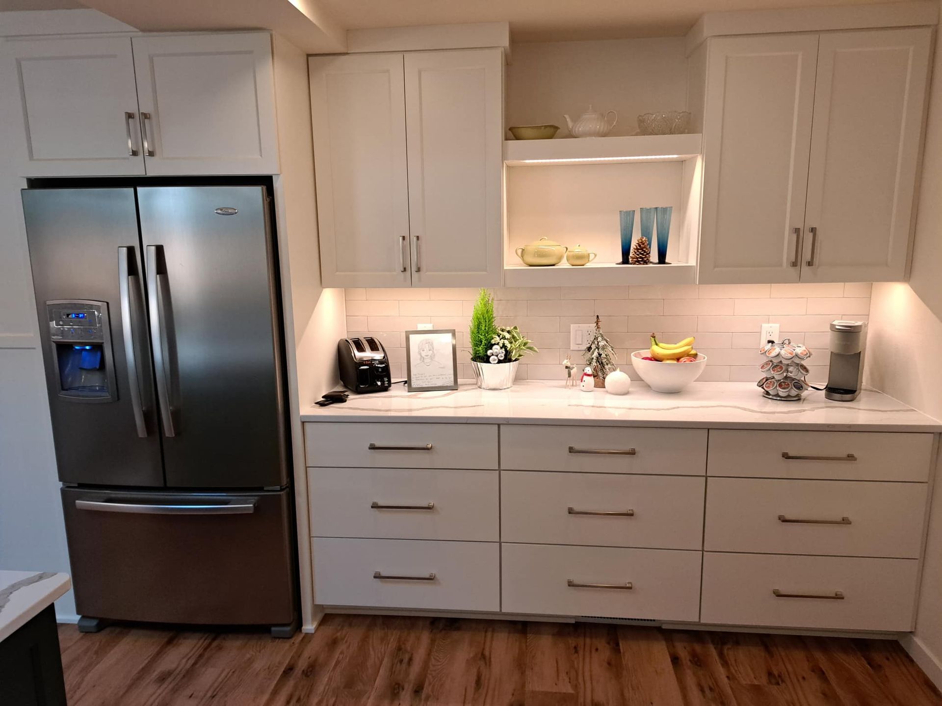A kitchen with white cabinets and a stainless steel refrigerator.