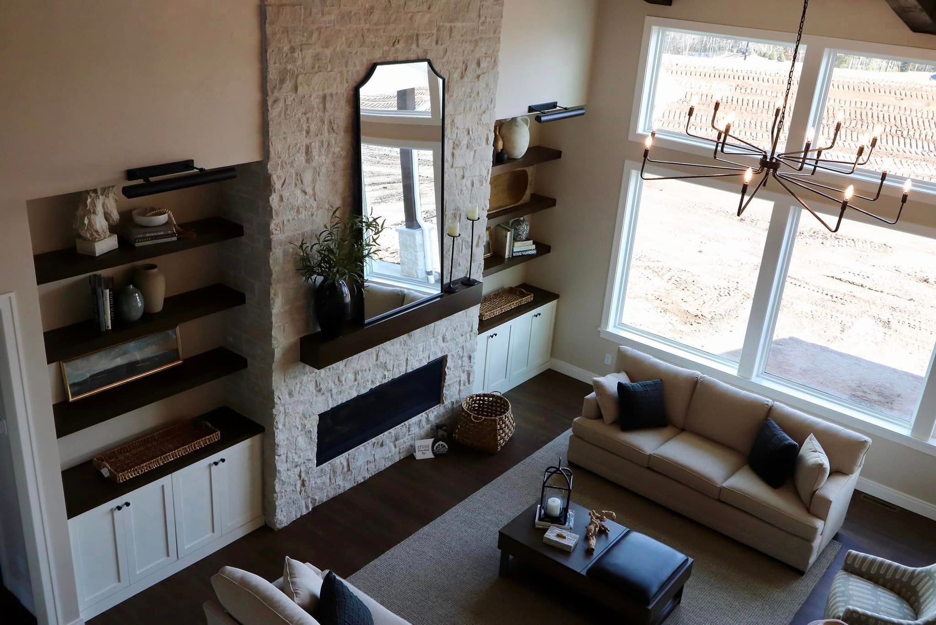High-angle view of a living room with fireplace, built-in shelves, and two couches, with large windows.