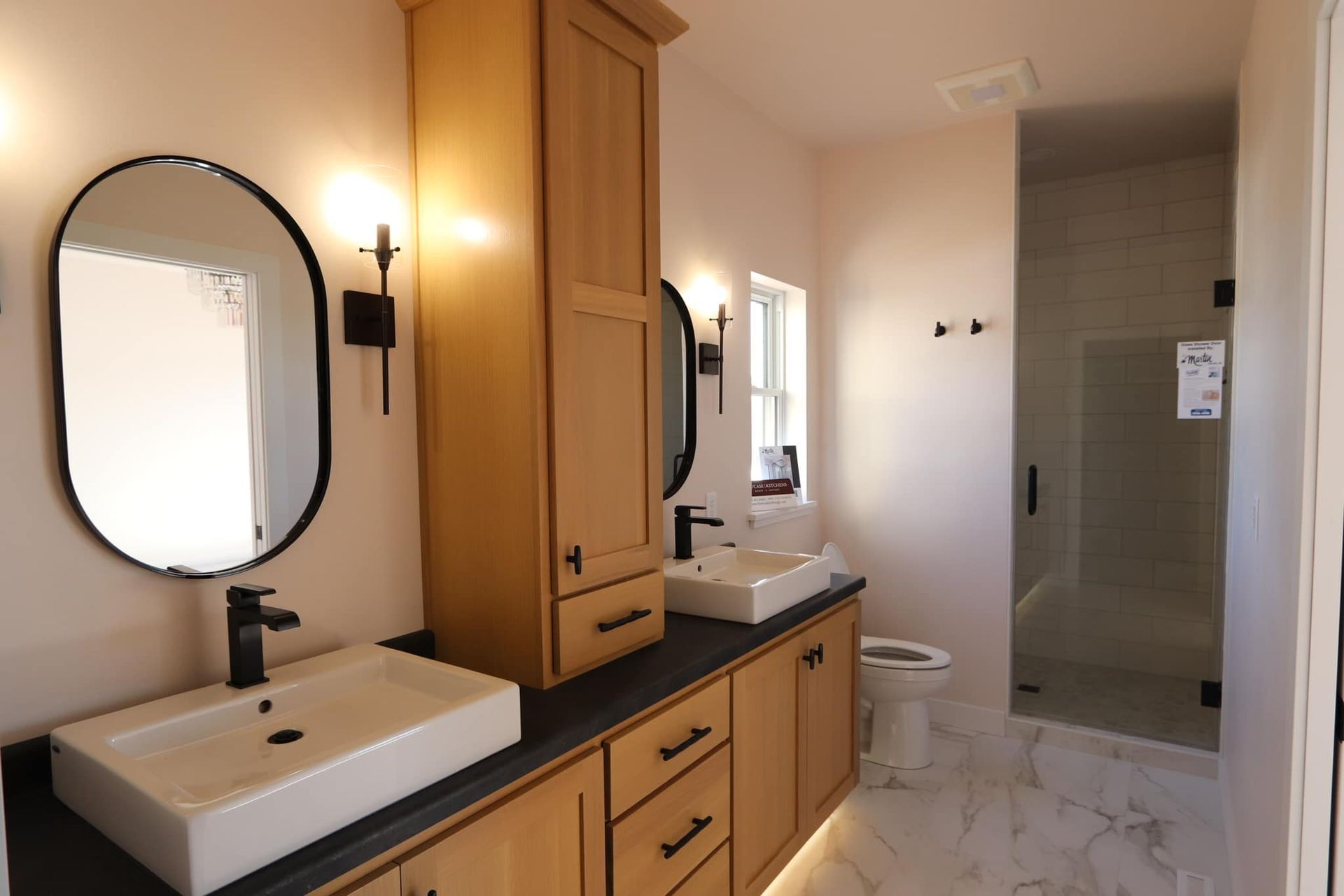 A bathroom with two sinks , a toilet and a shower.