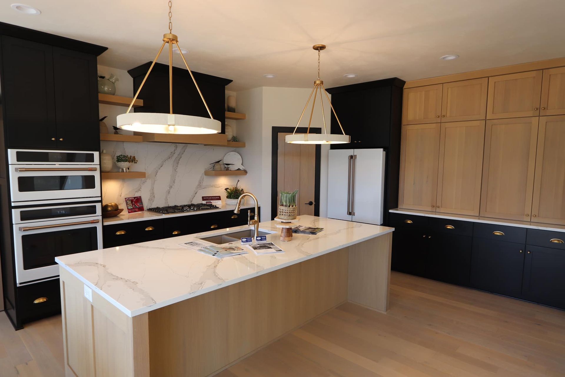 A kitchen with black cabinets , white counter tops , and a large island.