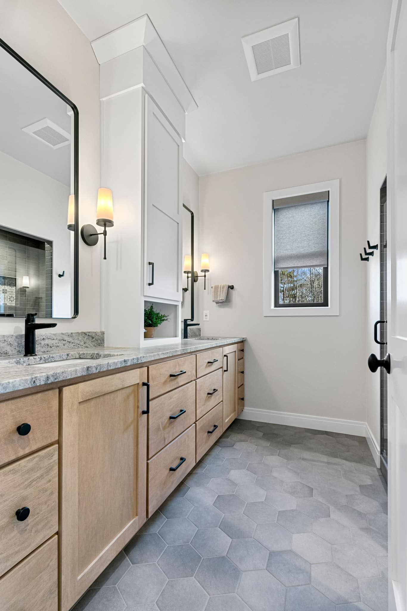 A bathroom with two sinks , a mirror and a window.