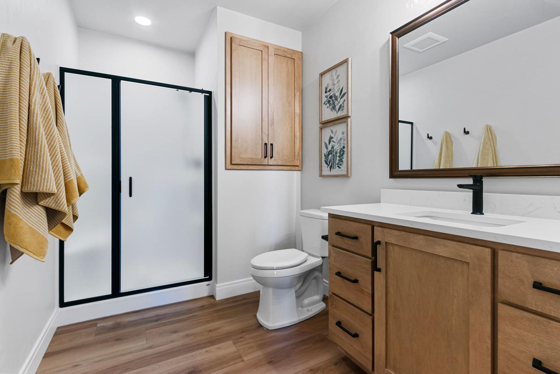 A bathroom with a toilet , sink , mirror and shower.
