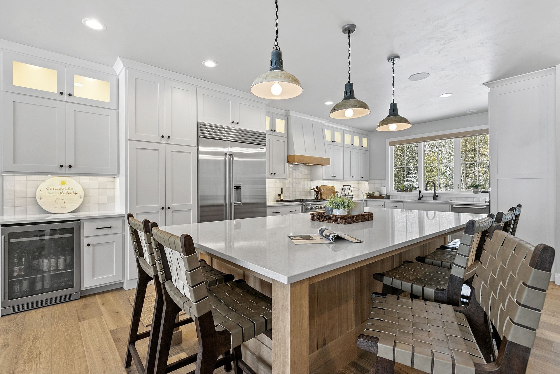 Spacious white kitchen with large island, stools, and pendant lights.
