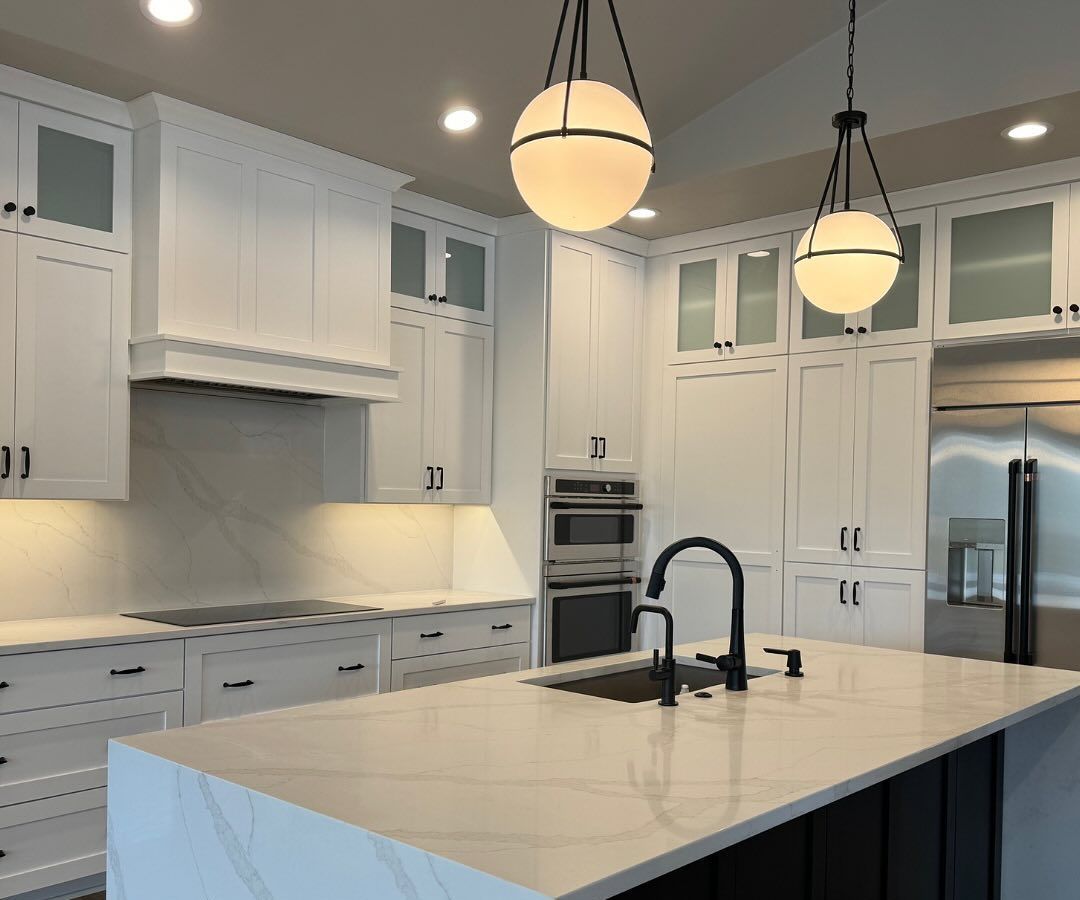 White kitchen with island, black faucet, and pendant lights.
