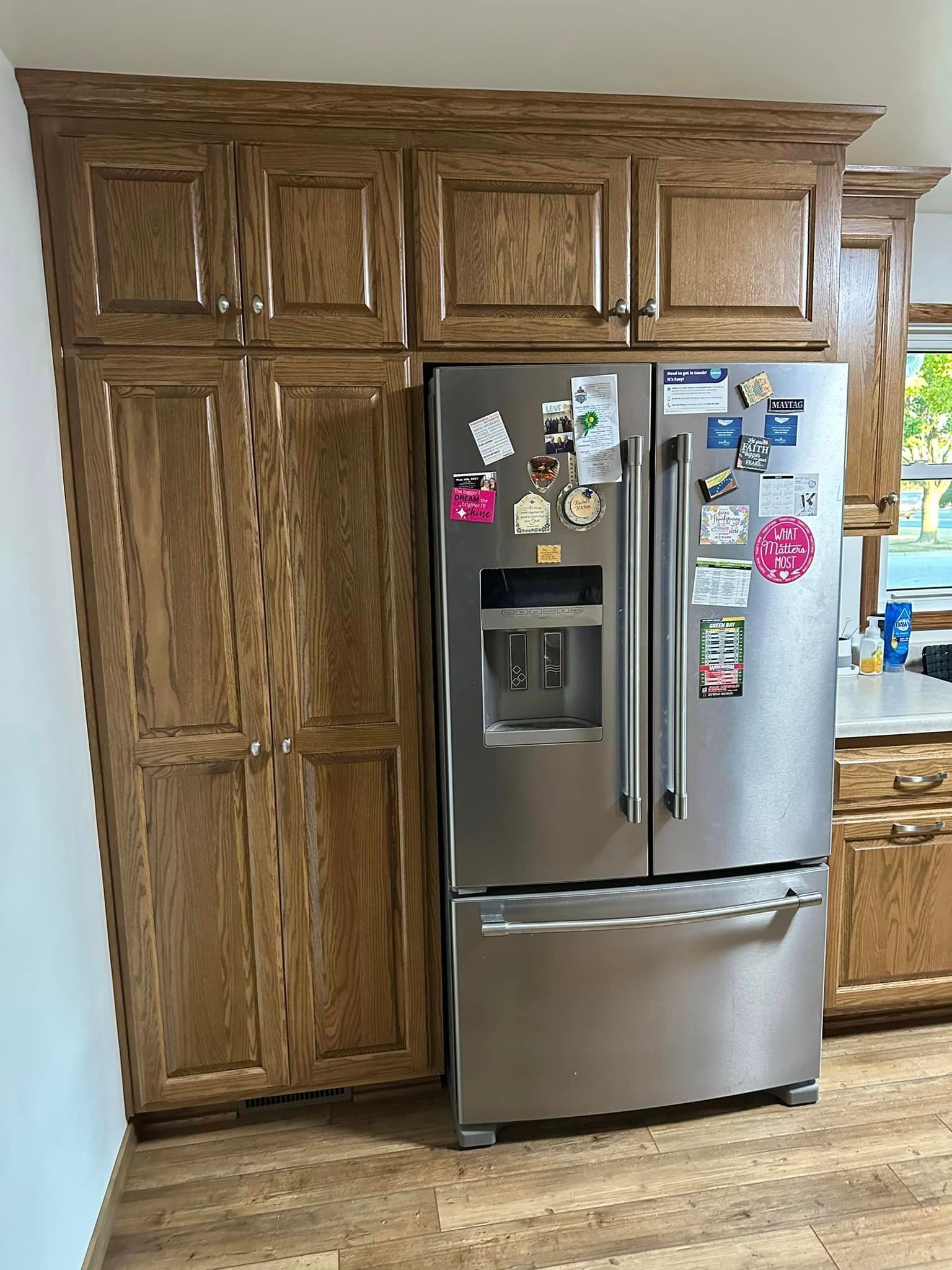 Wooden cabinets frame a stainless steel refrigerator in a kitchen.