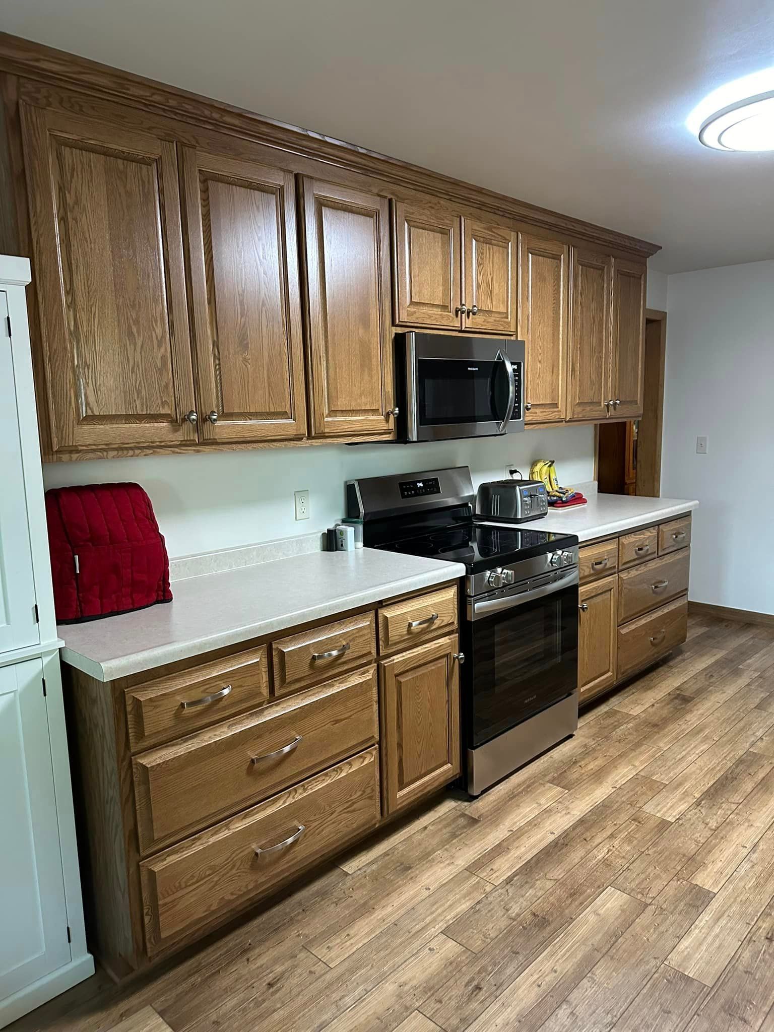 Kitchen with light brown wooden cabinets, white countertops, and stainless steel appliances.