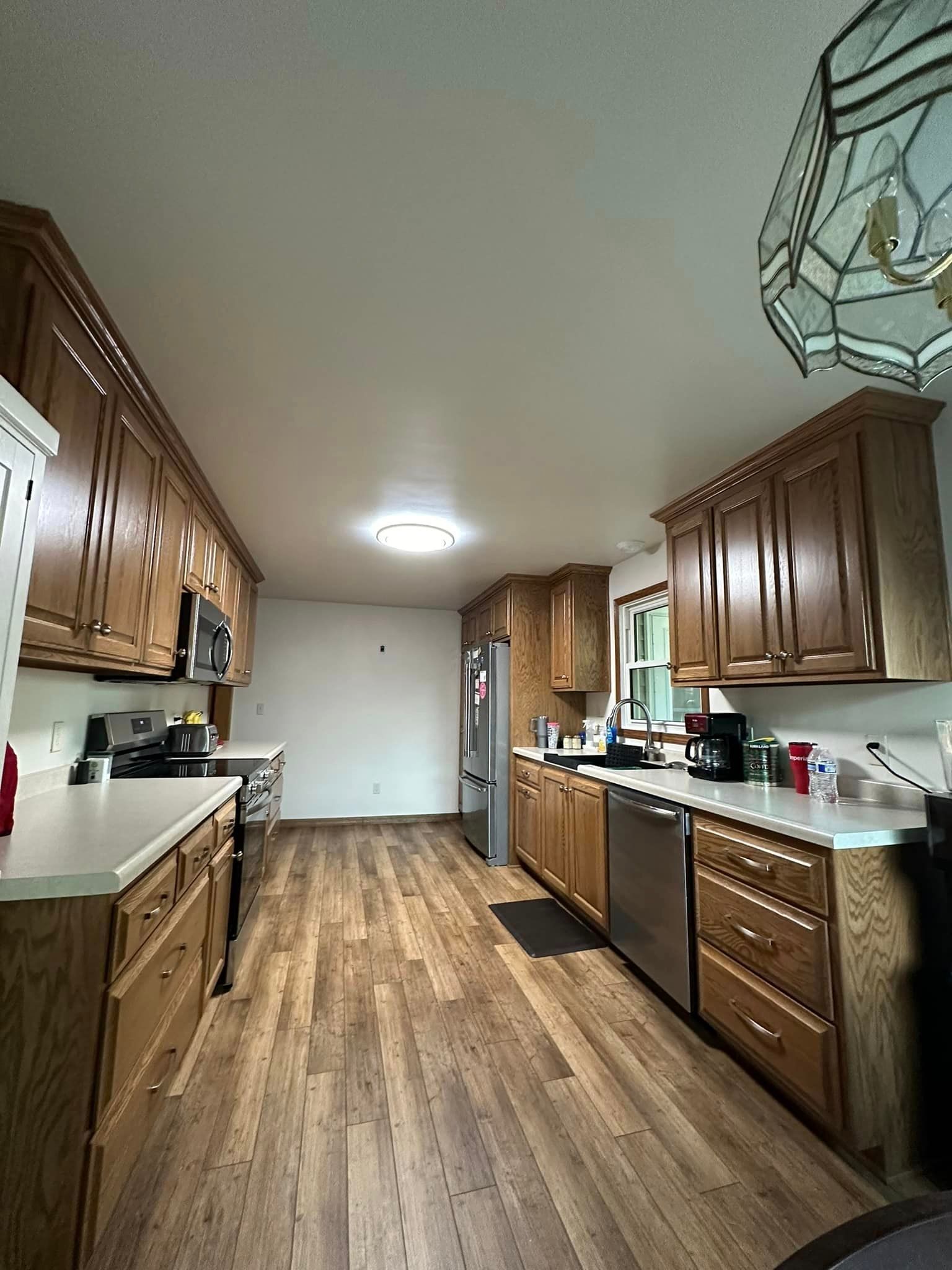 Kitchen with wood cabinets, stainless steel appliances, and wood-look flooring.