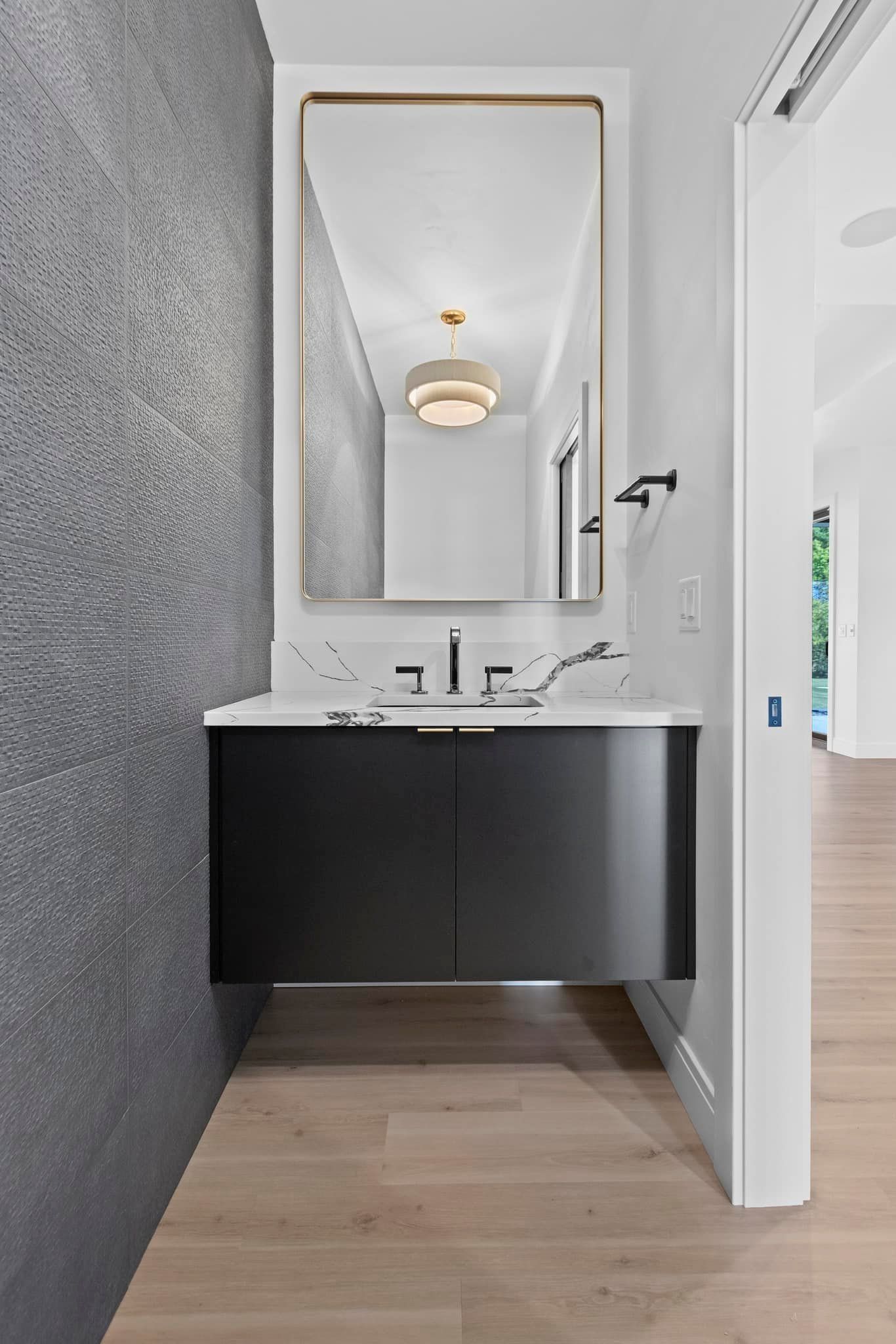 Powder room with a black floating vanity, large mirror, and textured gray wall.