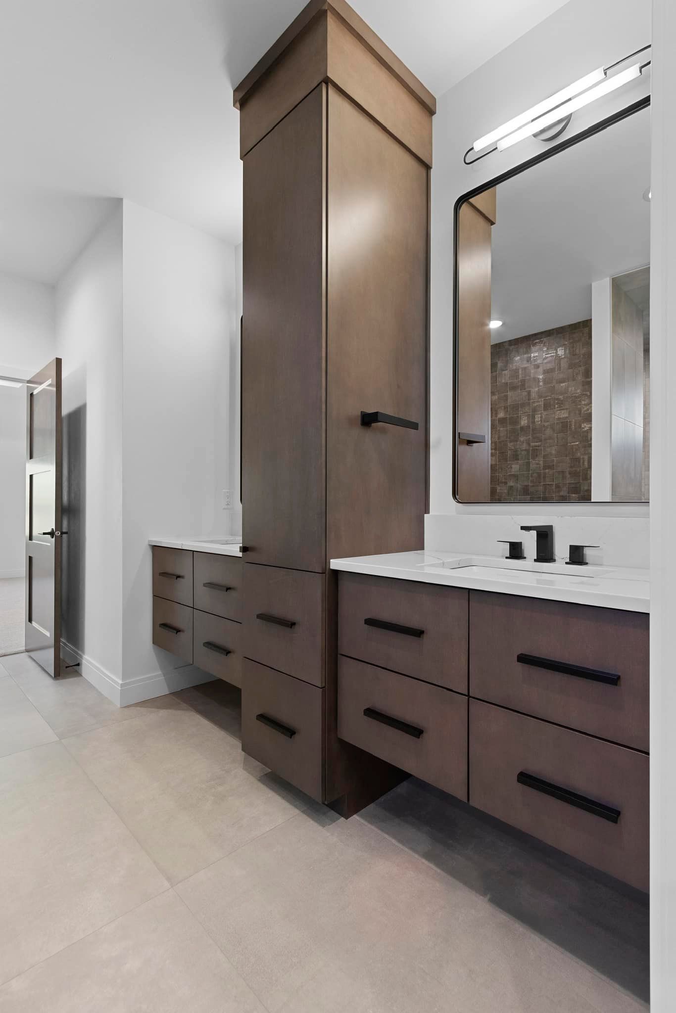 Bathroom with brown cabinets, white countertop, black fixtures, and large mirror.