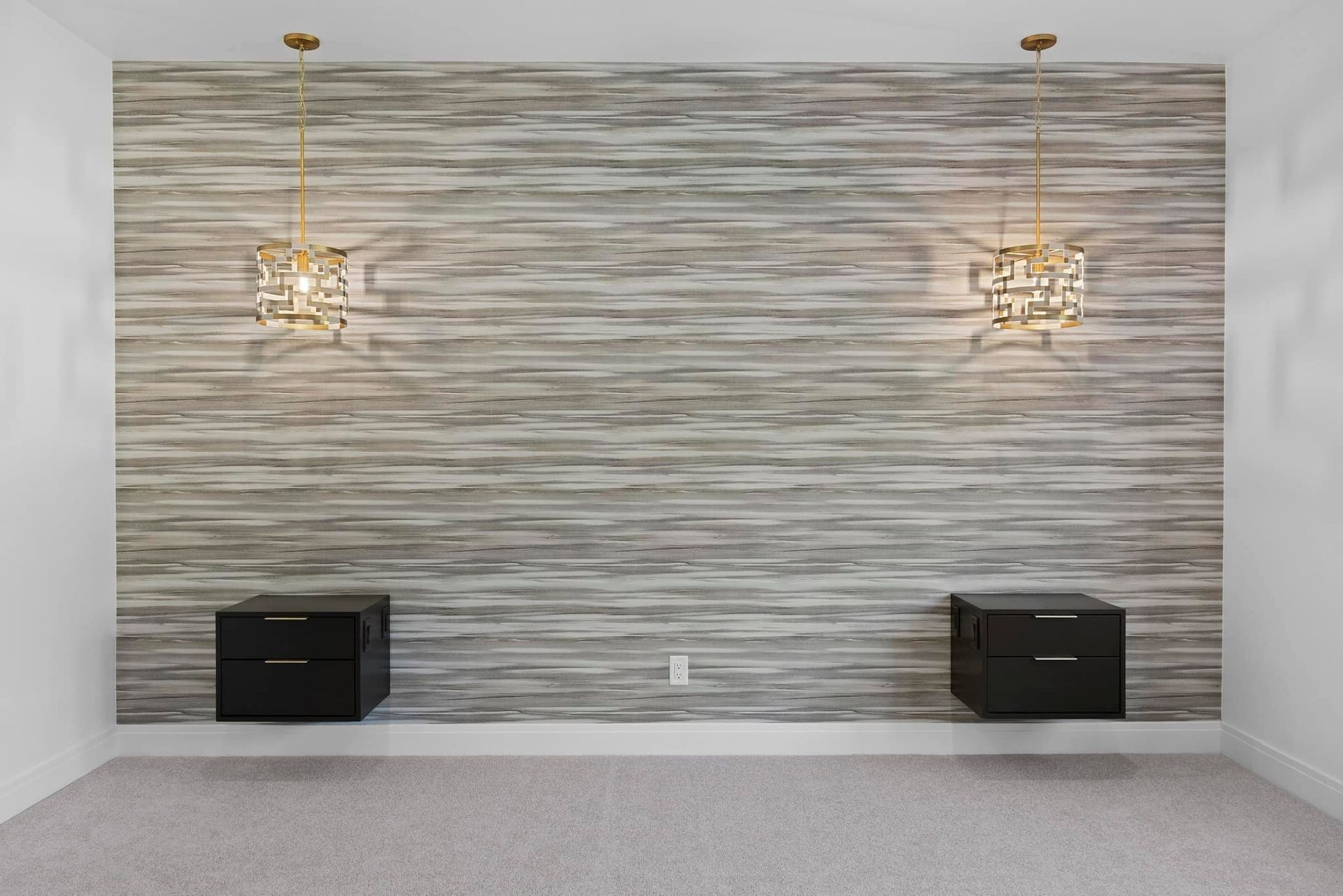 Bedroom with textured gray wall, two black floating nightstands, two ornate gold light fixtures, and carpet flooring.