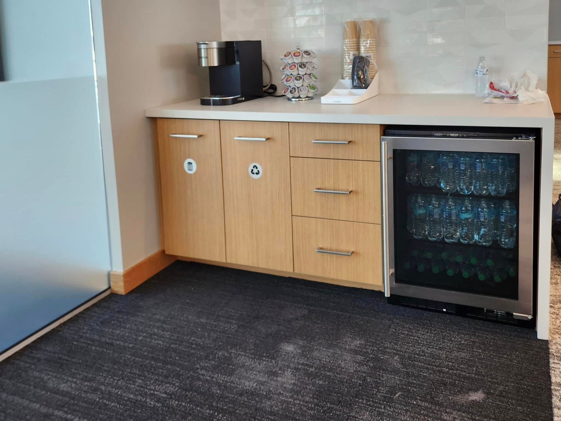 Coffee station with cabinet, drawers, mini-fridge, and coffee maker.