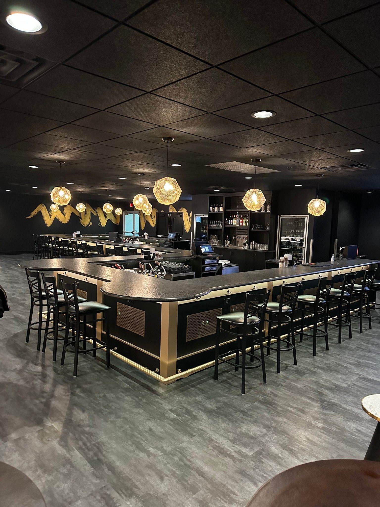A restaurant with a long bar and tables and chairs