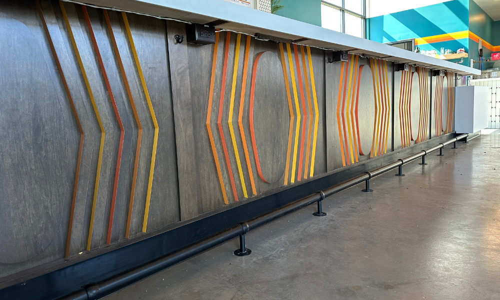 A long bar with a colorful design on the wall.