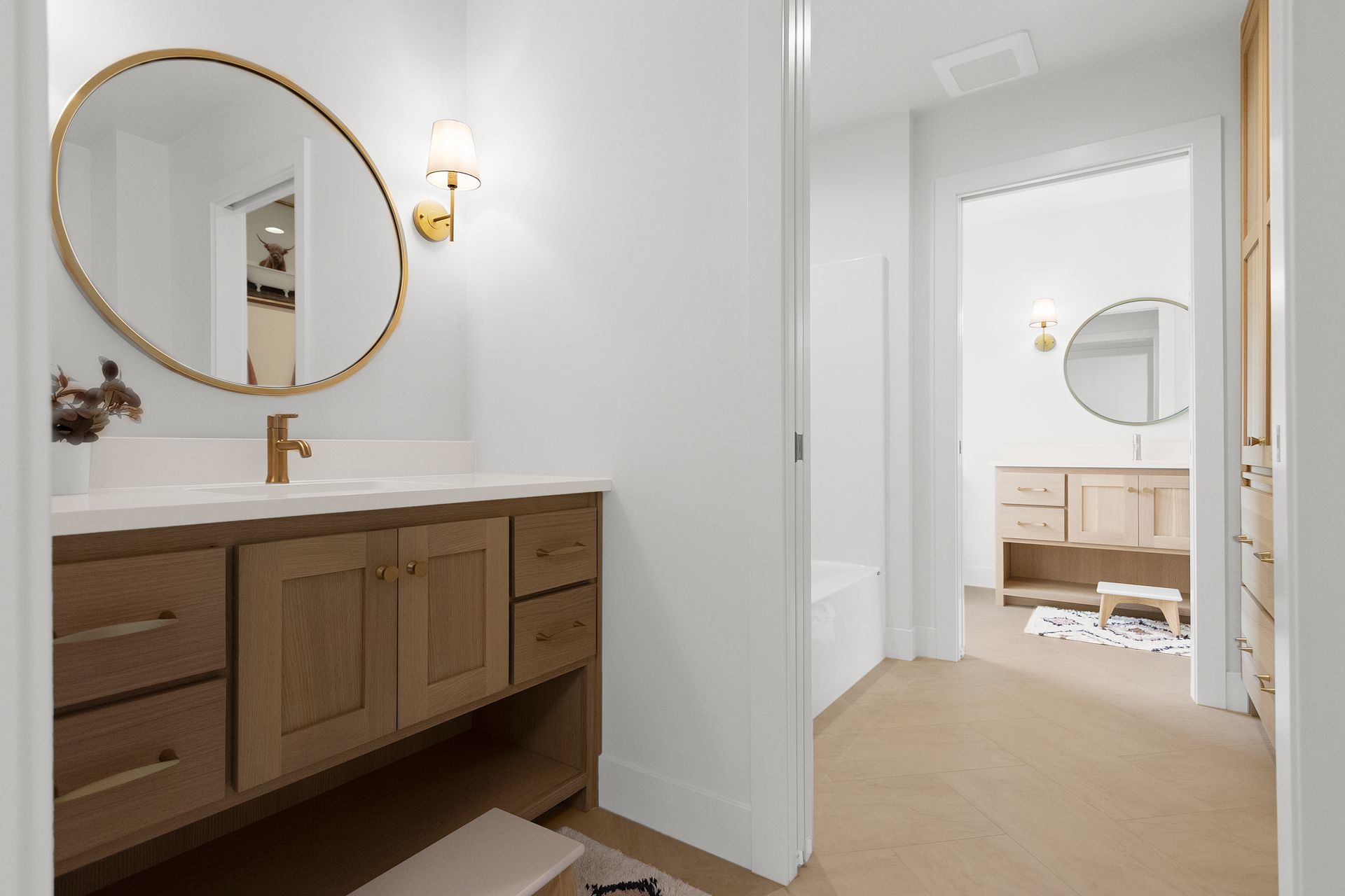 A bathroom with a sink , mirror , cabinets and drawers.