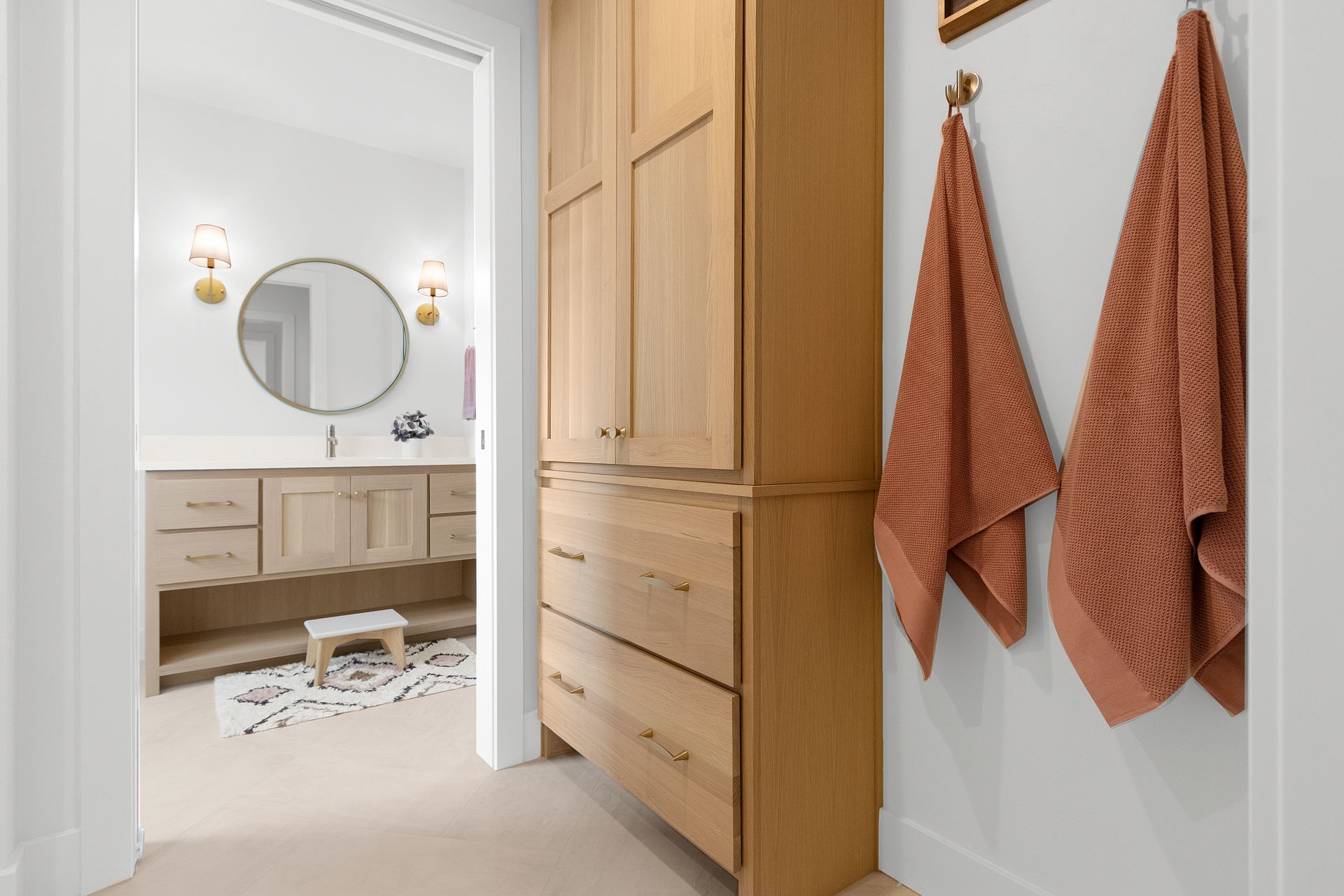 A bathroom with a dresser , sink , mirror and towels hanging on the wall.