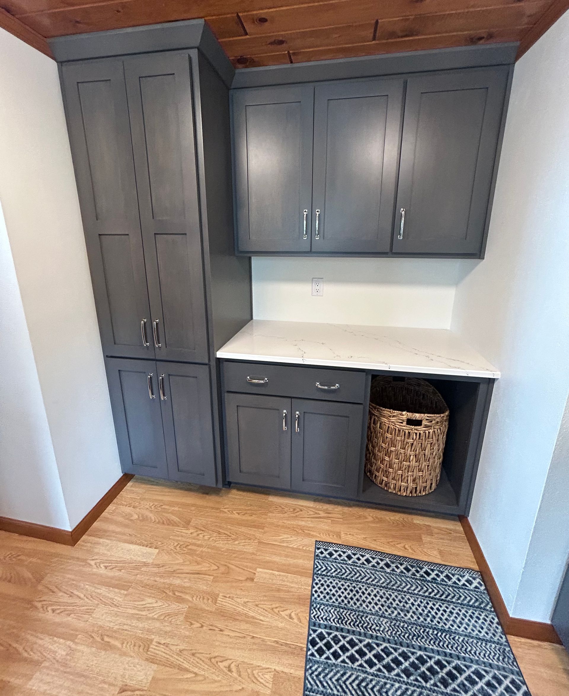 Laundry room with gray cabinets, white countertop, and woven basket.