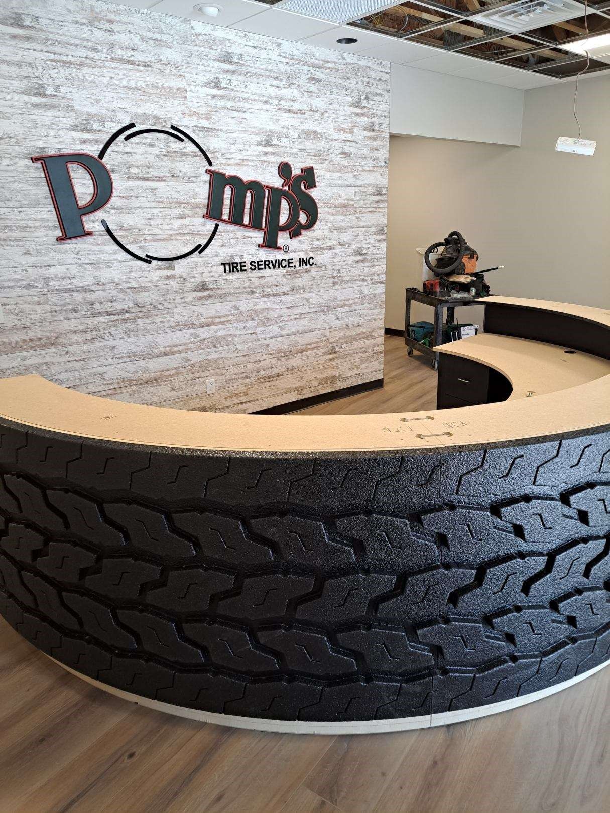 A reception desk made out of a tire and a brick wall.