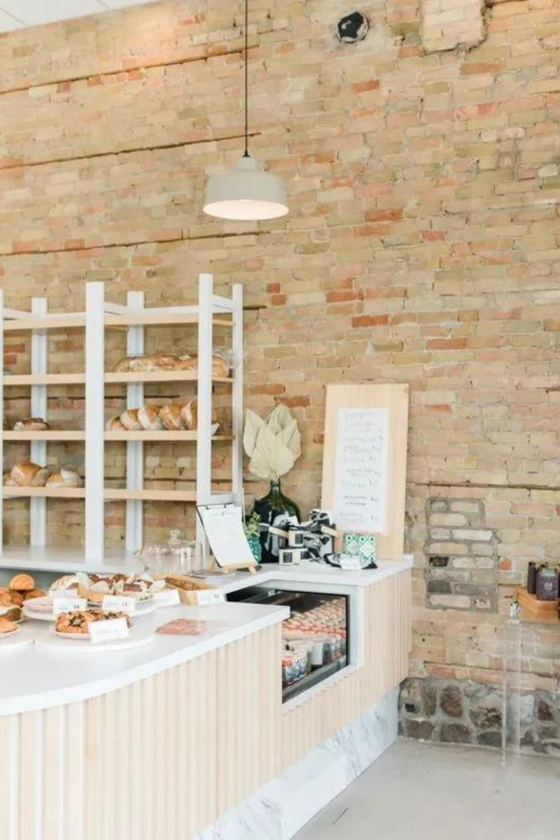 A bakery with a brick wall and a counter with a lot of food on it.