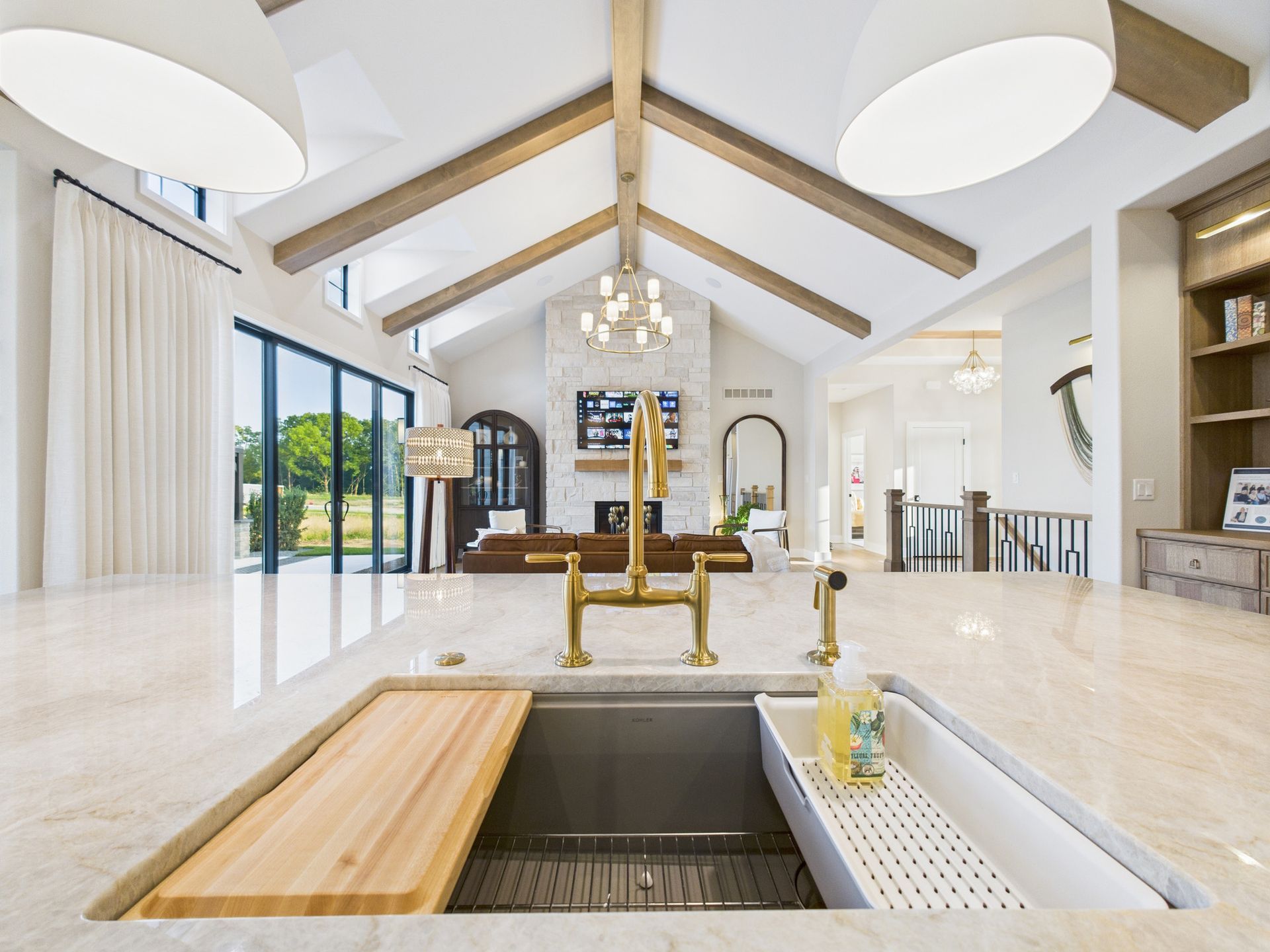 Spacious kitchen with island, gold fixtures, and vaulted ceiling with wooden beams.