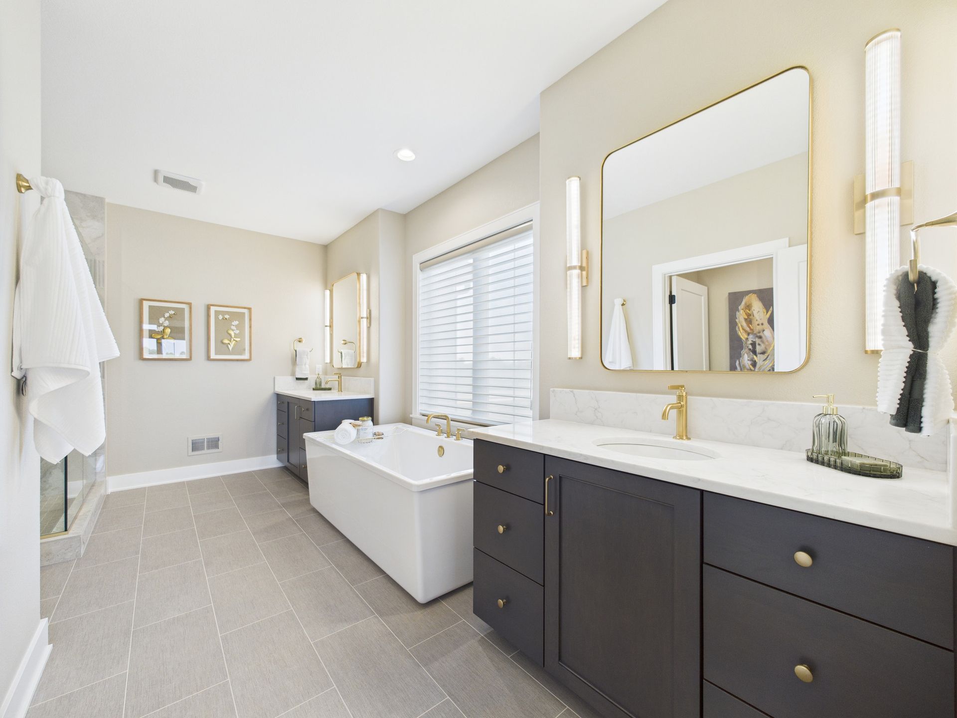 Modern master bathroom with dual vanities, a tub, and light-colored tile floor.