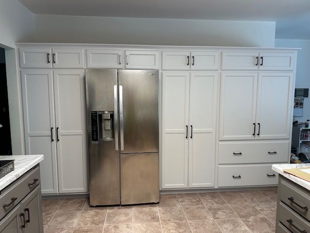 A kitchen with white cabinets and a stainless steel refrigerator