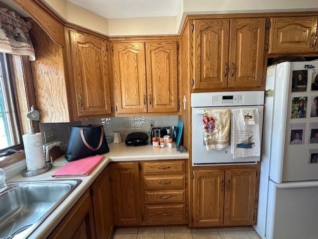 A kitchen with wooden cabinets , a refrigerator , and a sink.