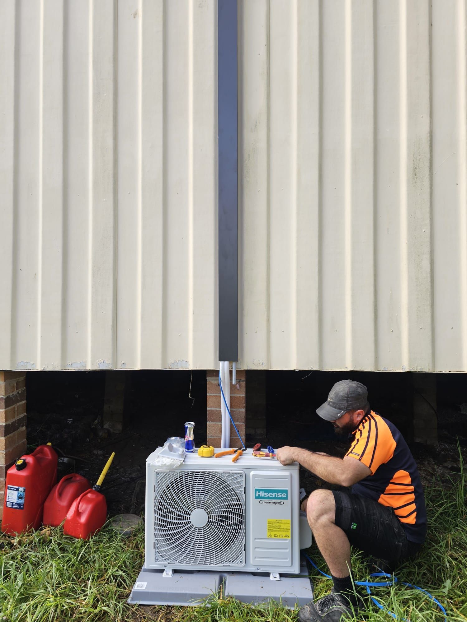 An air conditioner is sitting in the grass with leaves on it.
