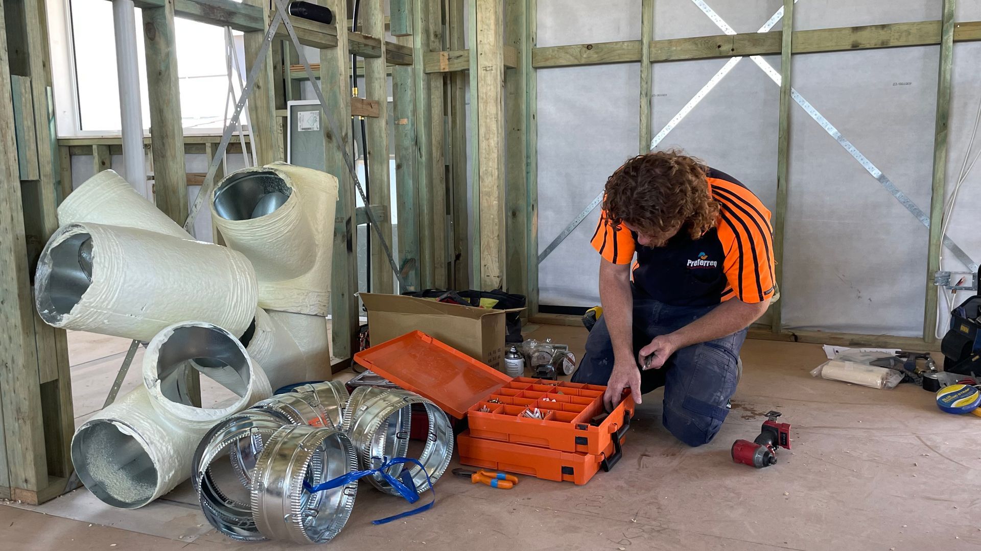 A man is installing an air conditioner in a room and giving a thumbs up.