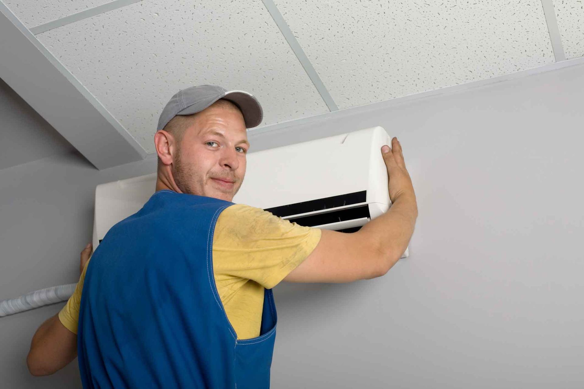A man is installing an air conditioner on a wall.