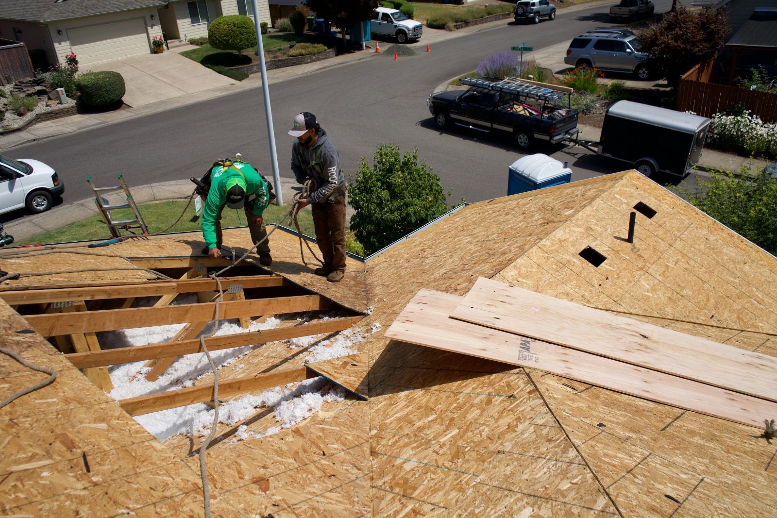 Two roofers working on a residential roof replacement; sunny day.