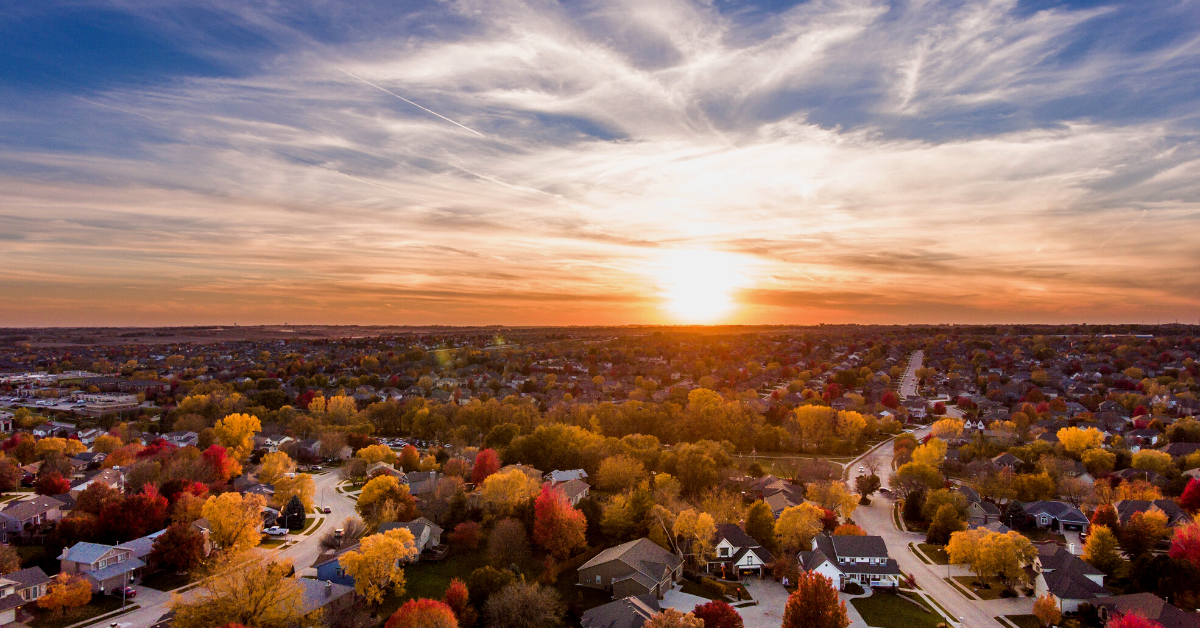 Sunset over a suburban area in Lebanon OR, colorful autumn trees in foreground, with a vibrant sky.