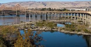 Bridge over water with mountains in the background; sunny day.