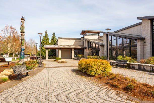 Building exterior with totem pole, walkways, and landscaping on a sunny day.