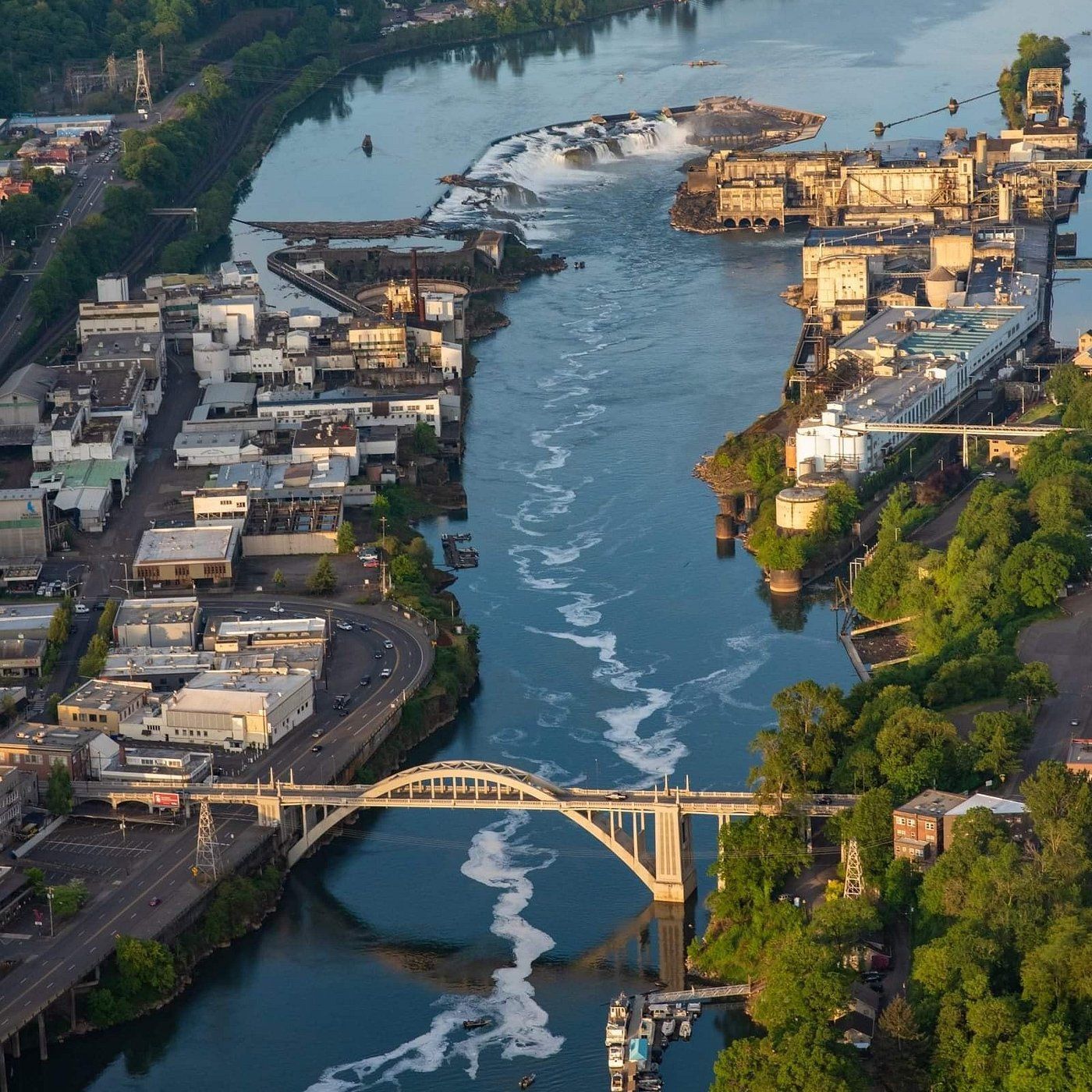 Aerial view of Spokane River with city buildings, a bridge, and a waterfall.