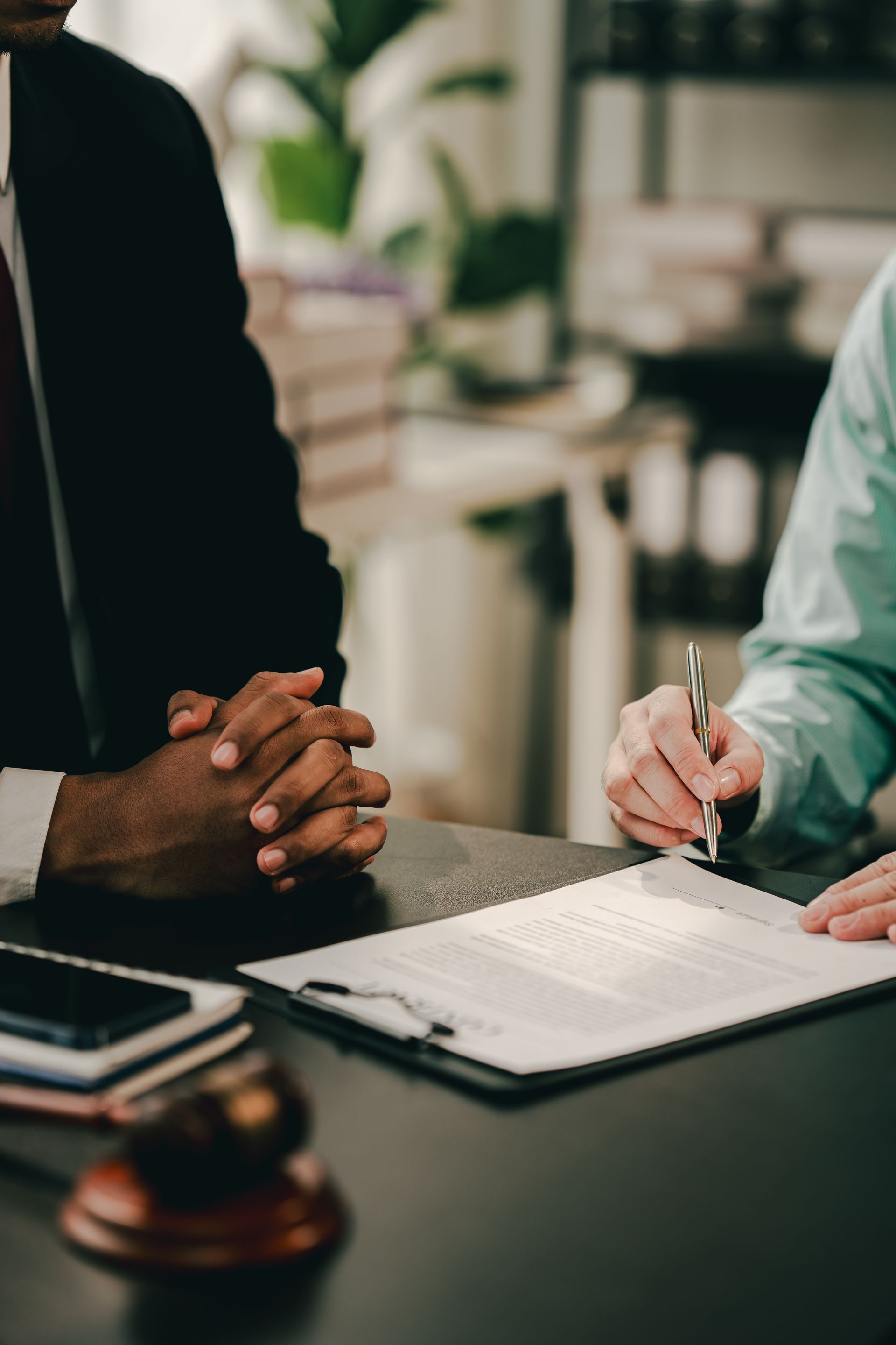 Two people at a desk signing a document in a meeting room