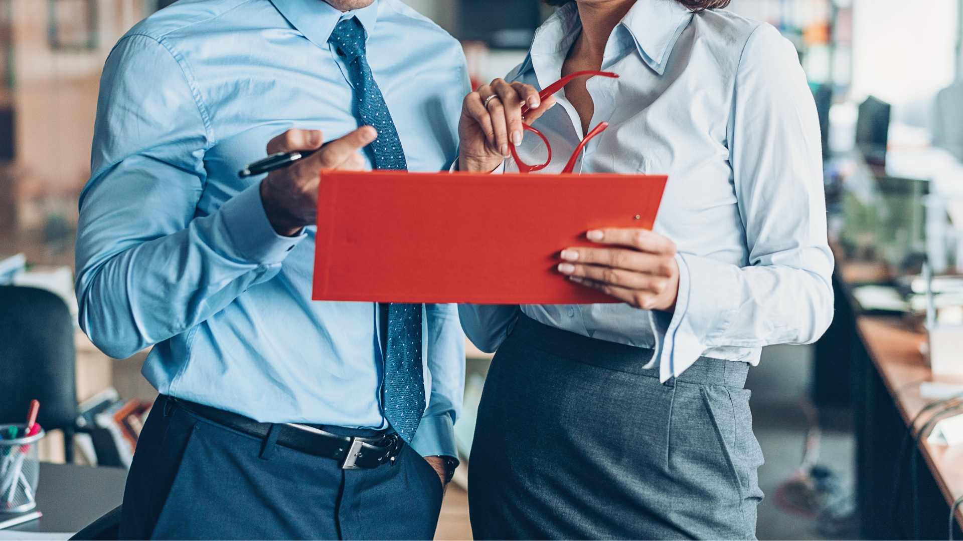 A man and a woman are standing next to each other holding a clipboard.