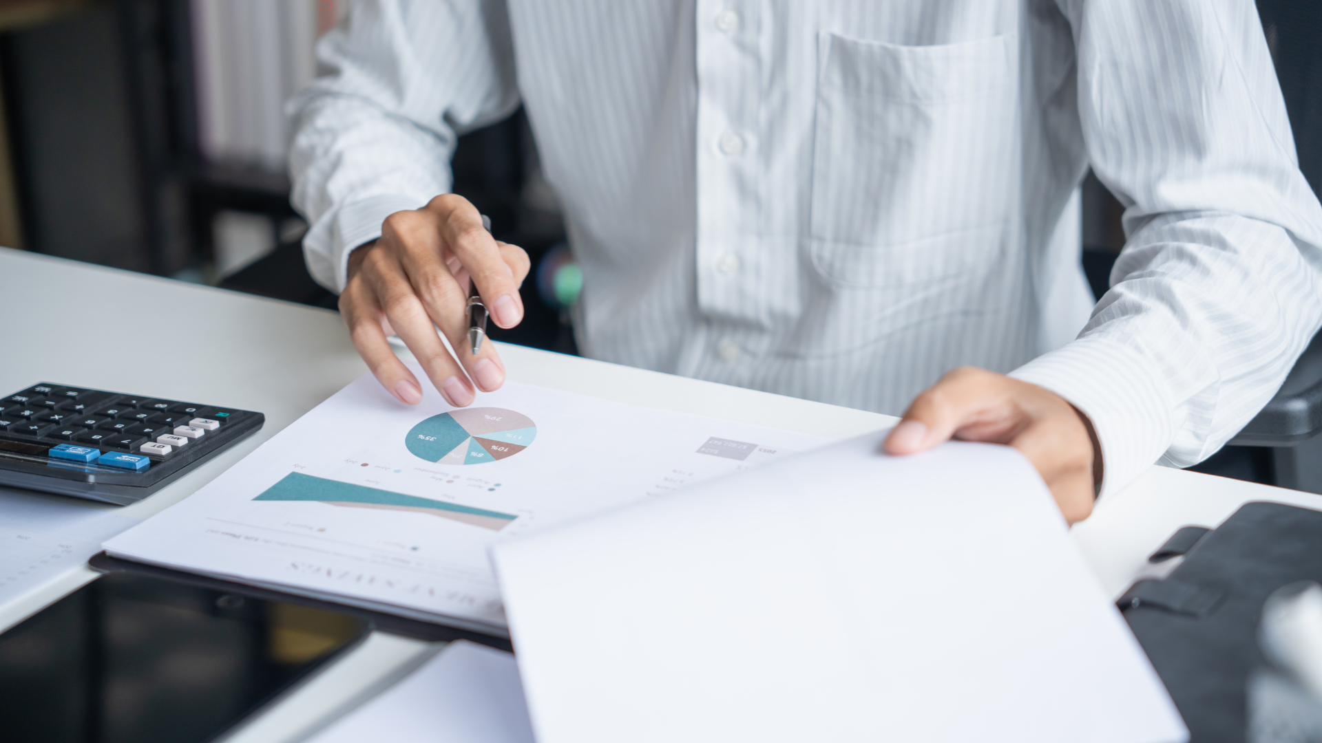 Business person analyzing financial documents and a pie chart, preparing for tax filing or IRS audit