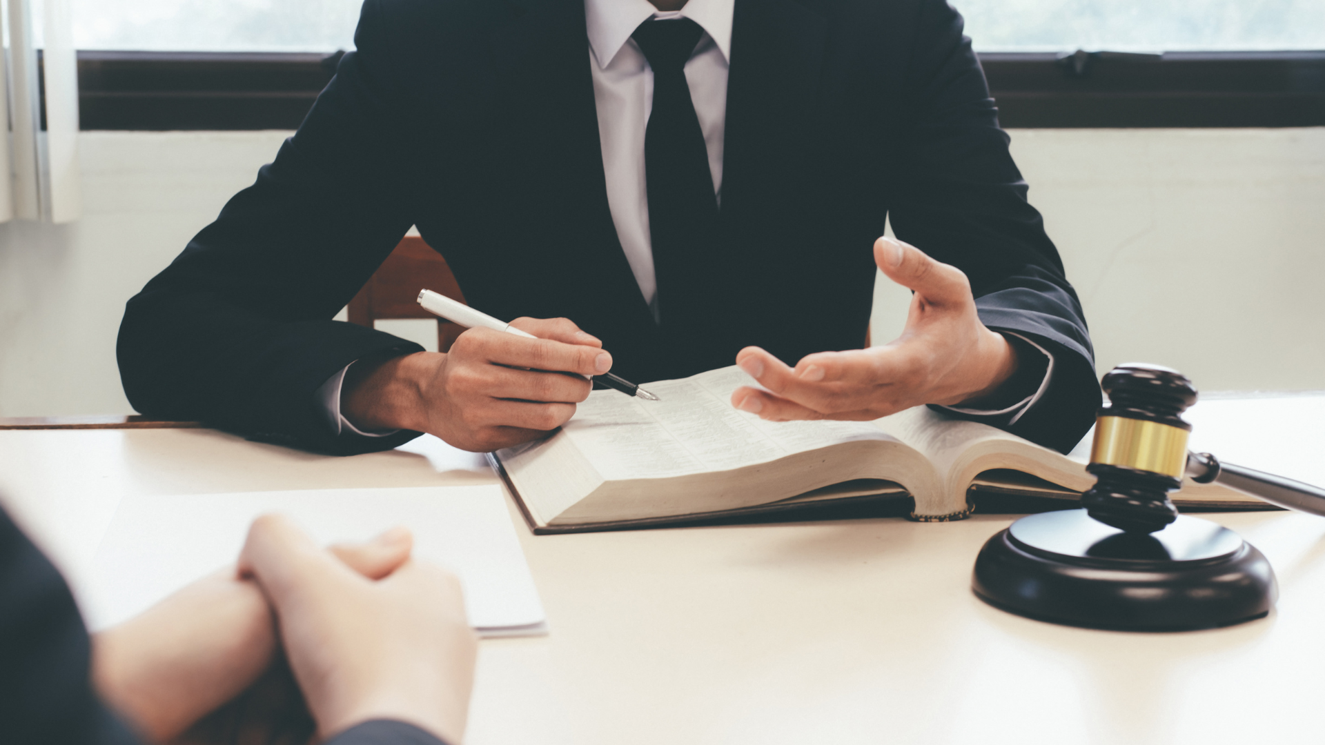 A man in a suit and tie is sitting at a table with a book and a gavel.