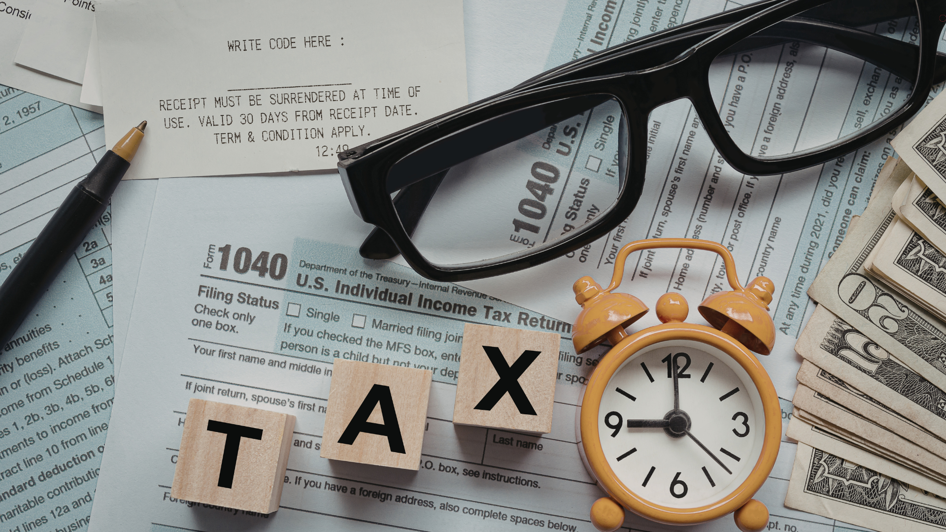 Tax documents, including a 1040 form, and wooden blocks spelling 'TAX,' with glasses and money, repr