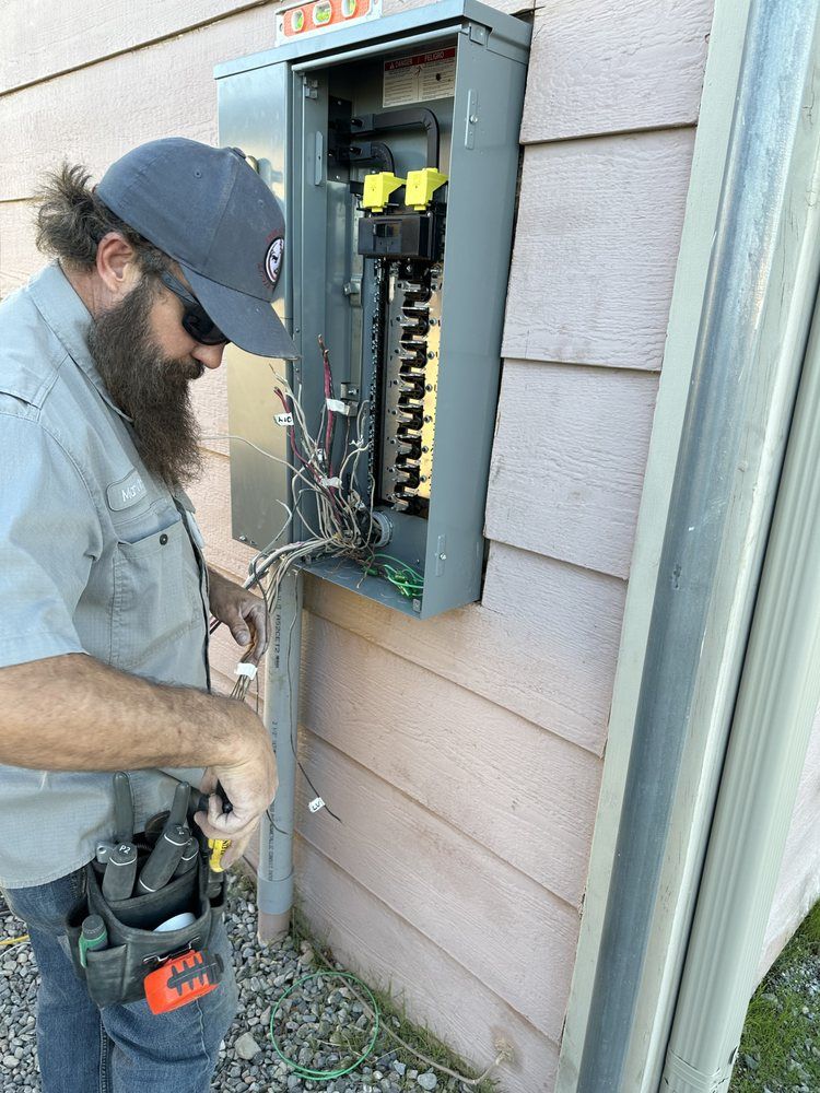 Electrician working on an outdoor electrical panel mounted on a house wall