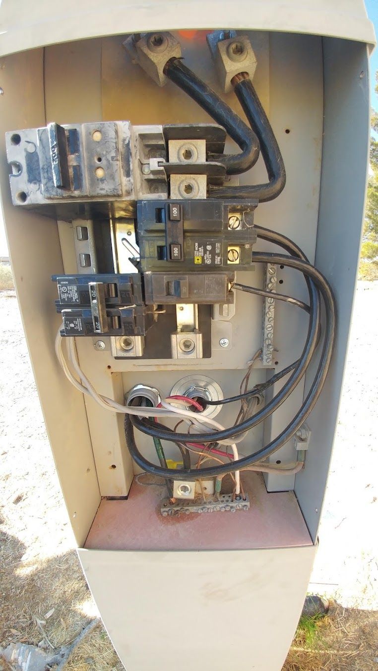 Open electrical panel with wiring, circuit breakers, and metal components inside a roadside cabinet