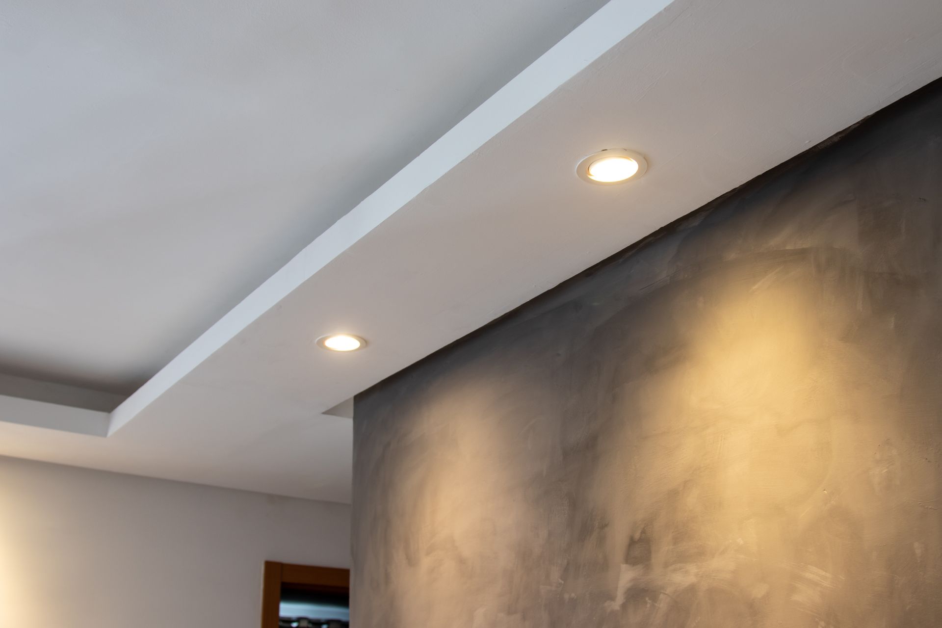 Modern interior wall with recessed ceiling lights and a textured dark accent wall