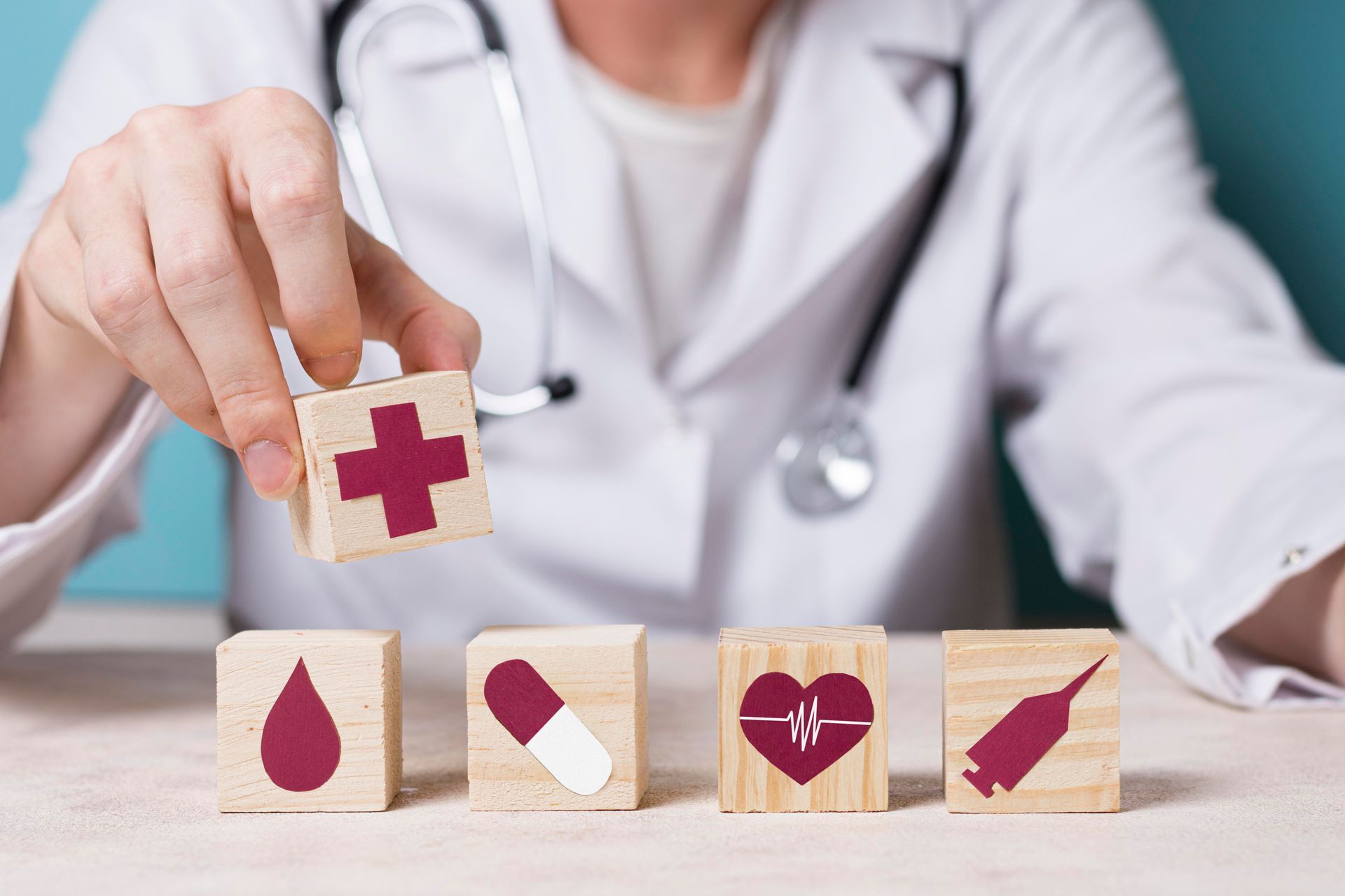 Doctor arranging medical icons on wooden blocks, including blood drop, pill, heart rate, and syringe.