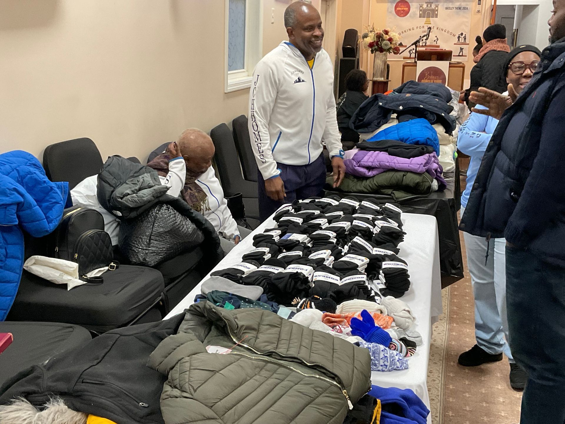 People at a clothing donation event: jackets, gloves, and socks on a table.