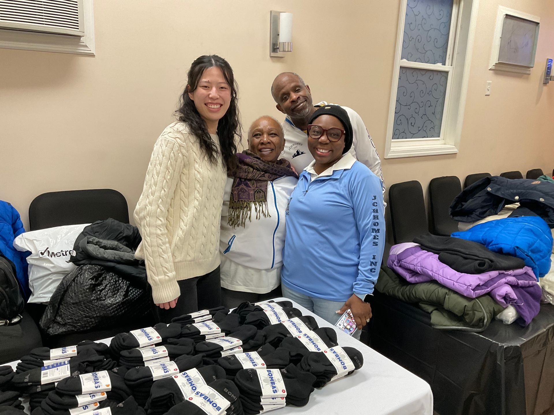 Four people smiling behind a table with stacks of black socks.