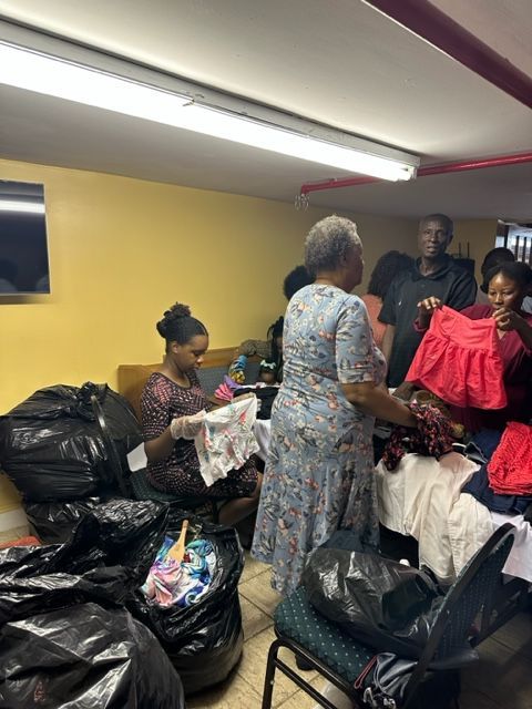 A group of people are standing in a room holding clothes.