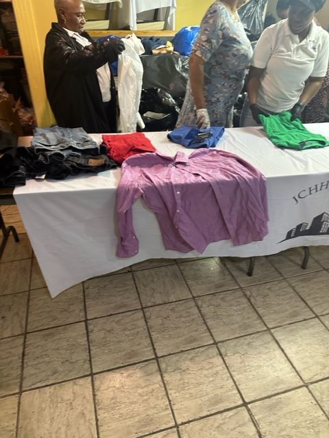 A group of people standing around a table with clothes on it