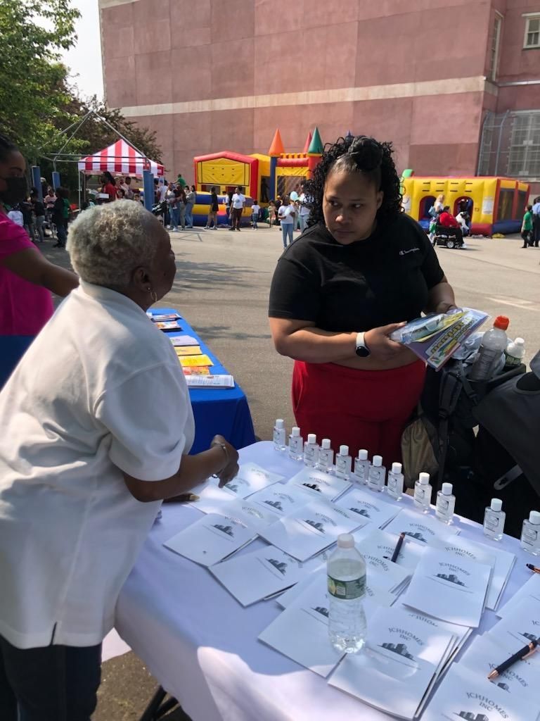 Two women are standing at a table with bottles of water and notebooks.