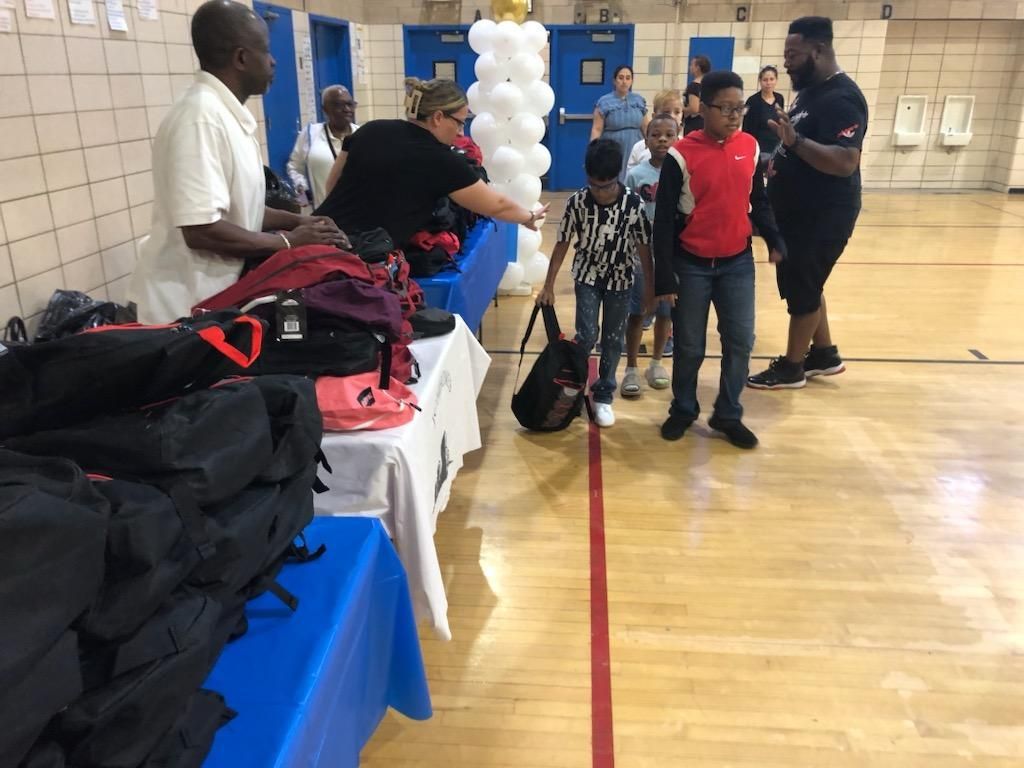 A group of people are standing around a table in a gym.