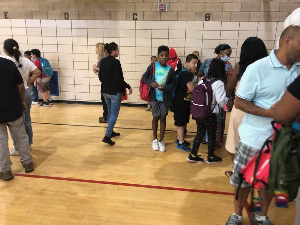 A group of people are standing on a gym floor.